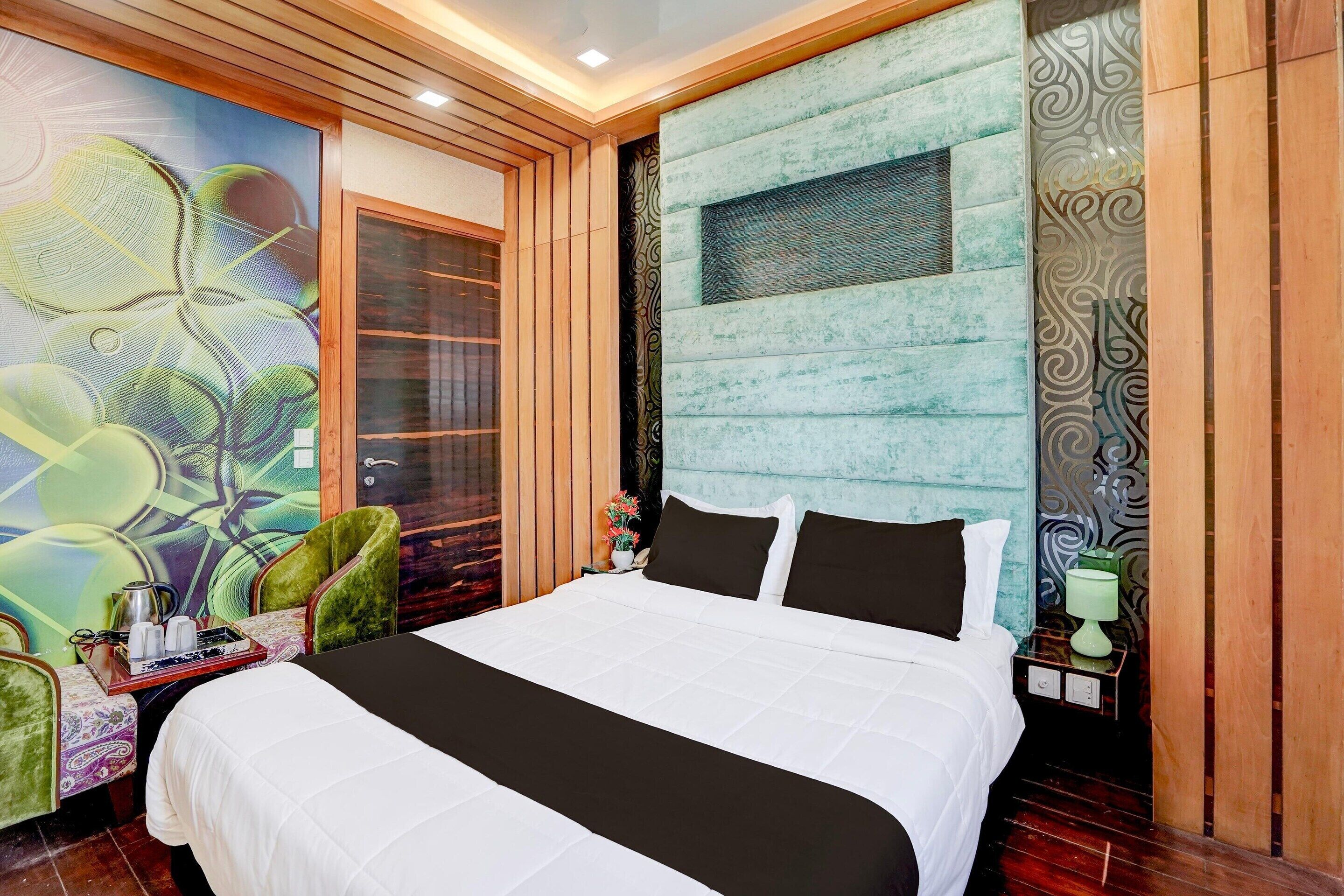 A hotel room with a large bed, a wooden headboard, a decorative wall, and a window with blinds.