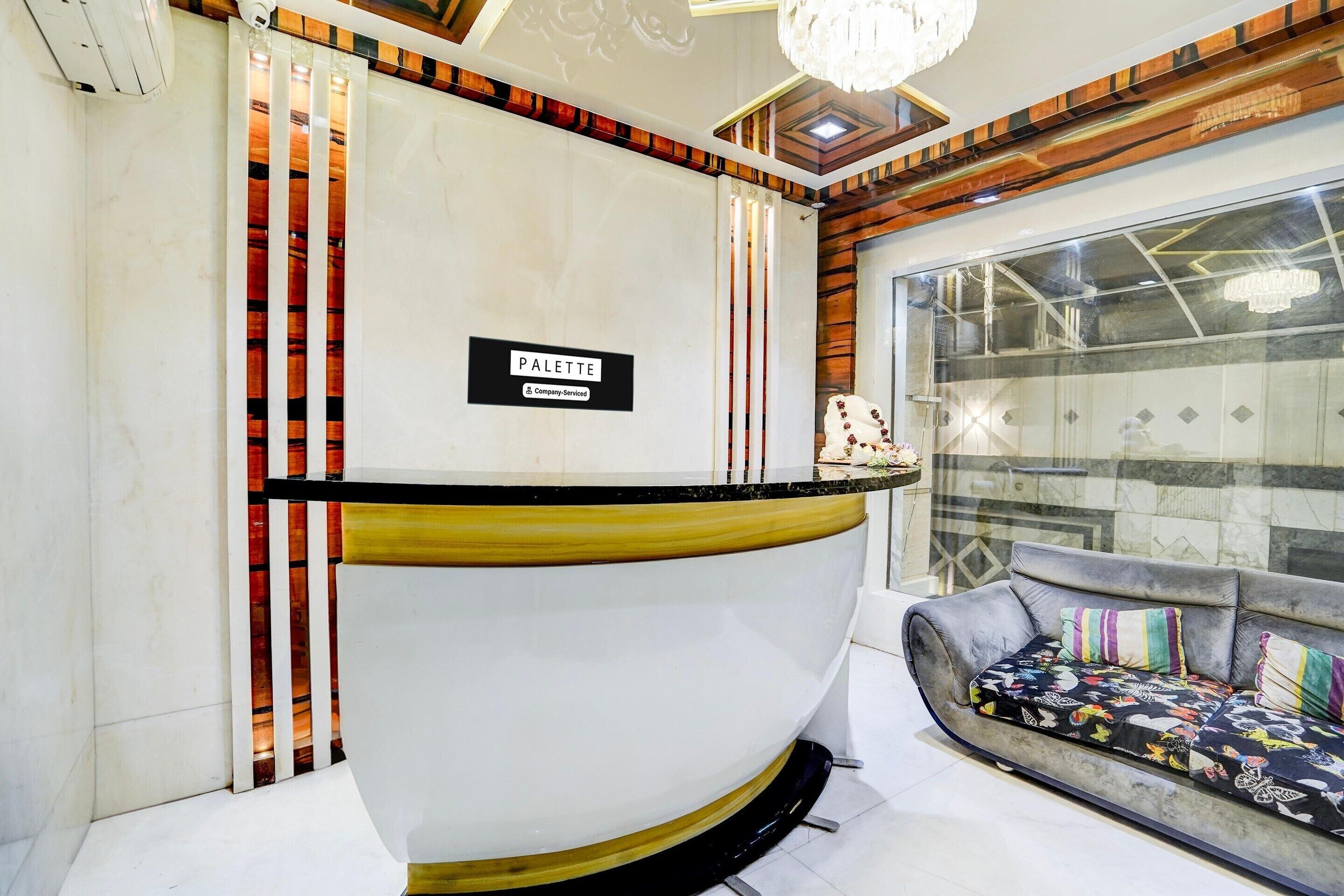 A reception area with a marble counter, a sign reading "PALETTE & Company Services," and a sofa with colorful cushions.