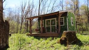 Eine kleine Holzhütte mit Veranda, umgeben von Bäumen.