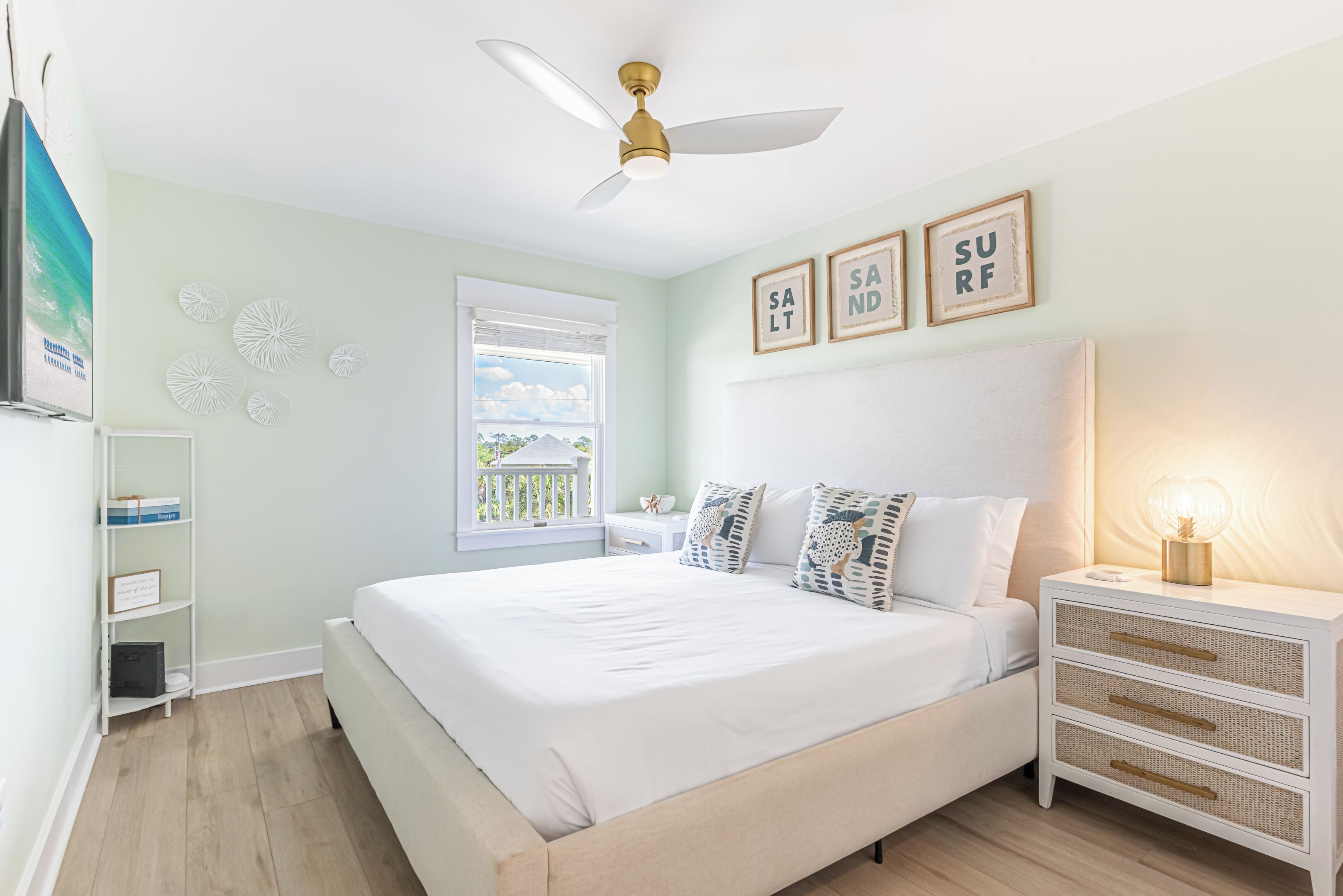 A bedroom with a bed, a nightstand, a ceiling fan, a window, and wall decorations.