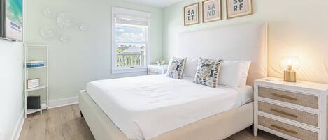 A bedroom with a bed, a nightstand, a ceiling fan, a window, and wall decorations.