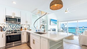 Una cocina moderna con armarios blancos, horno empotrado, microondas y una isla grande con lavamanos.