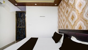 A hotel room with a bed, a headboard, a wall with a patterned design, and a window with a view. - Deluxehotel Mayur Residency (Gorakhpur)