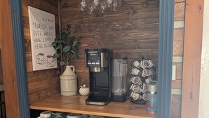 Un coin café équipé d’une machine à café, de tasses et d’un panneau.