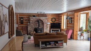Un salon chaleureux avec une cheminée, un canapé, un téléviseur et une table en bois.