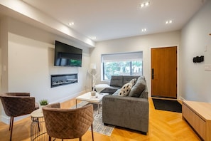 Ein modernes Wohnzimmer mit einem grauen Sofa, einem Couchtisch und zwei Sesseln.