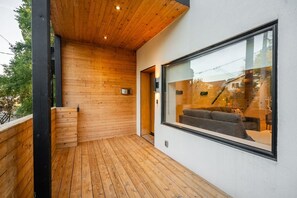 Ein modernes Zimmer mit Holzboden, einem großen Fenster und Blick auf eine Treppe.