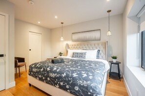 Ein Schlafzimmer mit einem großen Bett, einem Sessel, einem kleinen Tisch und einem Fenster.