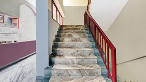 Un escalier en marbre avec une rampe rouge menant à un palier.