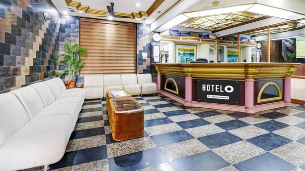 Un hall d’hôtel comprenant un comptoir d’enregistrement, un canapé, une table basse et une plante décorative.