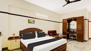 Une chambre d’hôtel comprenant un lit, une table de chevet, une commode, une chaise et une porte donnant sur une autre pièce.