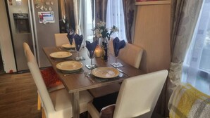 A dining table set with plates, glasses, and a vase of flowers. - Villa With Decking & Parking (Clacton-on-Sea)