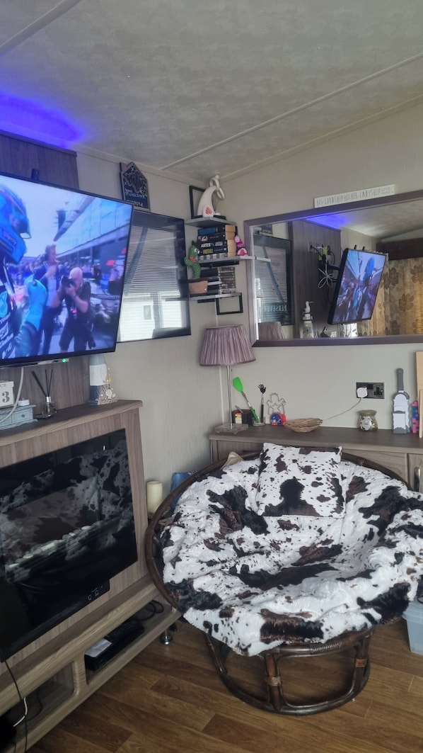 A living room with two TVs, a sofa, a lamp, and a decorative item on the wall.