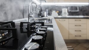A kitchen with a gas stove, a modern faucet, and a coffee maker.