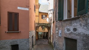 Un estrecho callejón con muros de piedra, un arco y la entrada de un edificio.