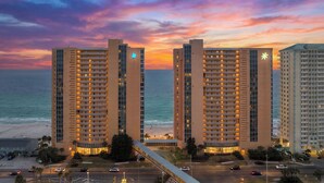 Un hotel de gran altura con varias plantas, vista al mar y cielo al atardecer.