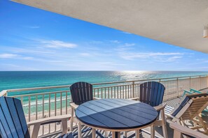 Een balkon met een tafel en stoelen, uitkijkend op de oceaan.