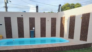 Una piscina con un borde empedrado, rodeada por un muro con un diseño de mosaicos.