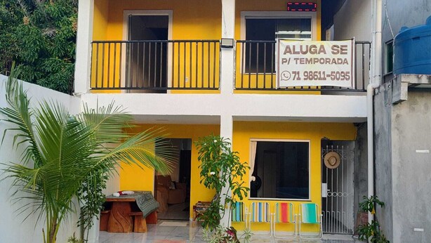 Un edificio de dos pisos con balcón, un letrero y un número de contacto.