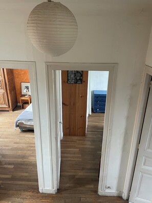 Una habitación con suelo de madera, una cama, un aparador y una puerta que da a otra estancia.