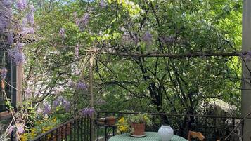 An outdoor patio with a round table, chairs, and potted plants.