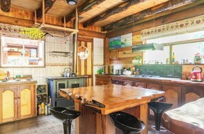 A rustic kitchen with wooden cabinets, a central island, and a stove.