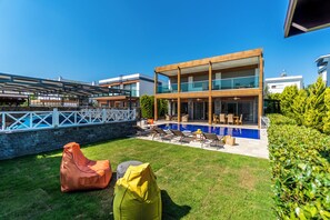 A modern two-story house with a swimming pool, outdoor seating, and a stone wall. - Luxury Villa - Private Pool - Prime Location (Bodrum)