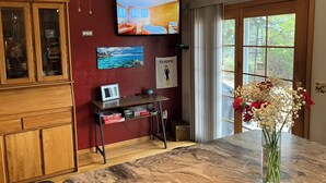 Una cocina con encimera de mármol, armarios de madera, ventilador de techo, televisor y ventana con vistas.
