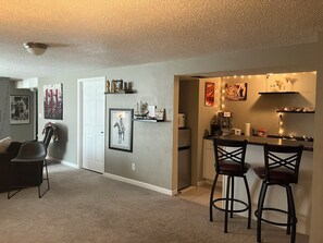 A compact living space with a kitchenette, a dining area with two bar stools, a refrigerator, a microwave, and a ceiling fan. - Four bedroom family home on cul de sac near East Boulder Rec Centre - (Boulder)