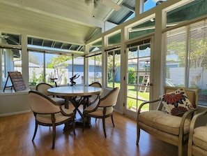 A sunroom with a round table and chairs, large windows, and a view of the outdoors. - Gorgeous Villa 10 Mins to Disney (Santa Ana)