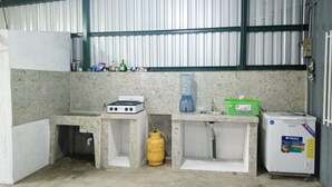 Cozinha compacta com fogão a gás, filtro de água, pia e um refrigerador pequeno.