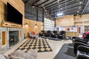 A spacious room with a fireplace, a large flat-screen TV, and multiple seating areas.
