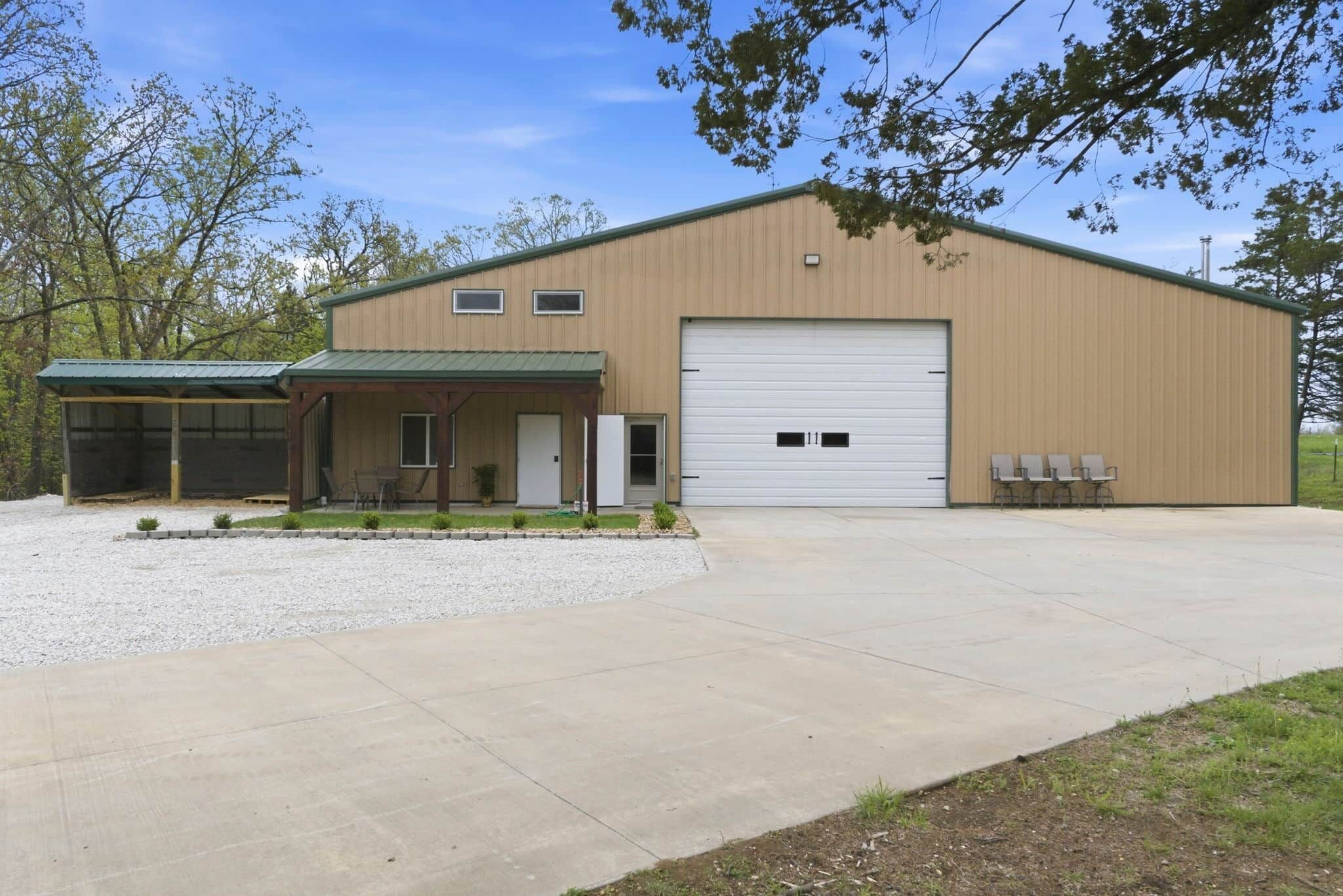 A single-story building with a covered entrance, a large garage door, and a gravel driveway.