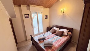 A bedroom with a bed, a nightstand, a window, and a wall-mounted light fixture.