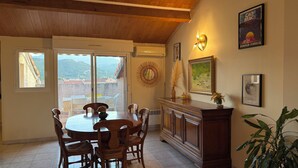 A dining area with a round table, chairs, a wooden cabinet, and a view through a glass door.