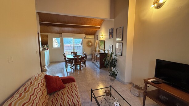 A living room with a sofa, TV, dining area, and kitchen.