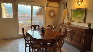A dining area with a wooden table and chairs, a decorative mirror, and a view of mountains through the glass door.