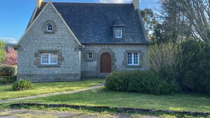 A stone house with a pitched roof, a central entrance, and a small porch. - Charming house in Le Faou, a "little town of character", between land and sea. (Le Faou)