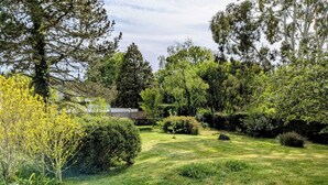 A well-maintained garden with a variety of trees and shrubs, a paved pathway, and a fenced area. - Charming house in Le Faou, a "little town of character", between land and sea. (Le Faou)