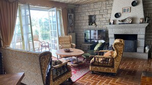 A living room with a stone fireplace, a television, and a dining area with a table and chairs. - Charming house in Le Faou, a "little town of character", between land and sea. (Le Faou)