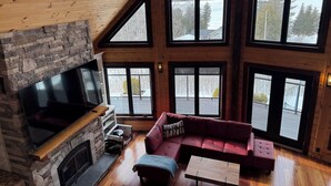 Una sala de estar amplia con chimenea de piedra, un sofá modular rojo grande y un televisor de pantalla plana.