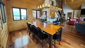 Interior de una cabaña de madera con comedor, cocina y sala de estar.