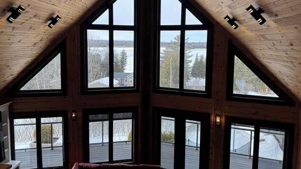 Una habitación con techo inclinado, ventanas grandes y vistas a un paisaje nevado.