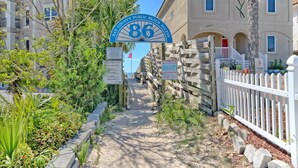 Ein Weg, der zu einem Gebäude führt, mit einem Schild, das 'Bay County Public Beach Access' und ein 'Parkverbot'-Schild zeigt.