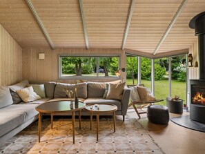 A cozy living room with a sofa, two round tables, a fireplace, and a view of the outdoors. - "Niela" - 700m from the sea by Interhome (Græsted)