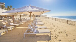 A beach with rows of sun loungers and umbrellas, a clear sky, and the ocean in the background. -  Luxurious 5-Diamond Resort with 2 bedrooms at Villa La Valencia in Los Cabos. (San José del Cabo)
