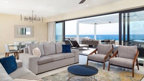 A modern living room with a sofa, chairs, a dining table, and a view of the ocean. -  Luxurious 5-Diamond Resort with 2 bedrooms at Villa La Valencia in Los Cabos. (San José del Cabo)