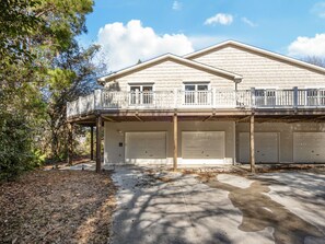 A two-story house with a balcony, two garages, and a driveway.