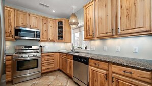 Eine Küche mit Holzausstattung, Edelstahlgeräten und einer Arbeitsplatte aus Granit.