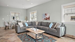 Ein Wohnzimmer mit einer Eckcouch, einem Couchtisch und einem gemusterten Teppich.
